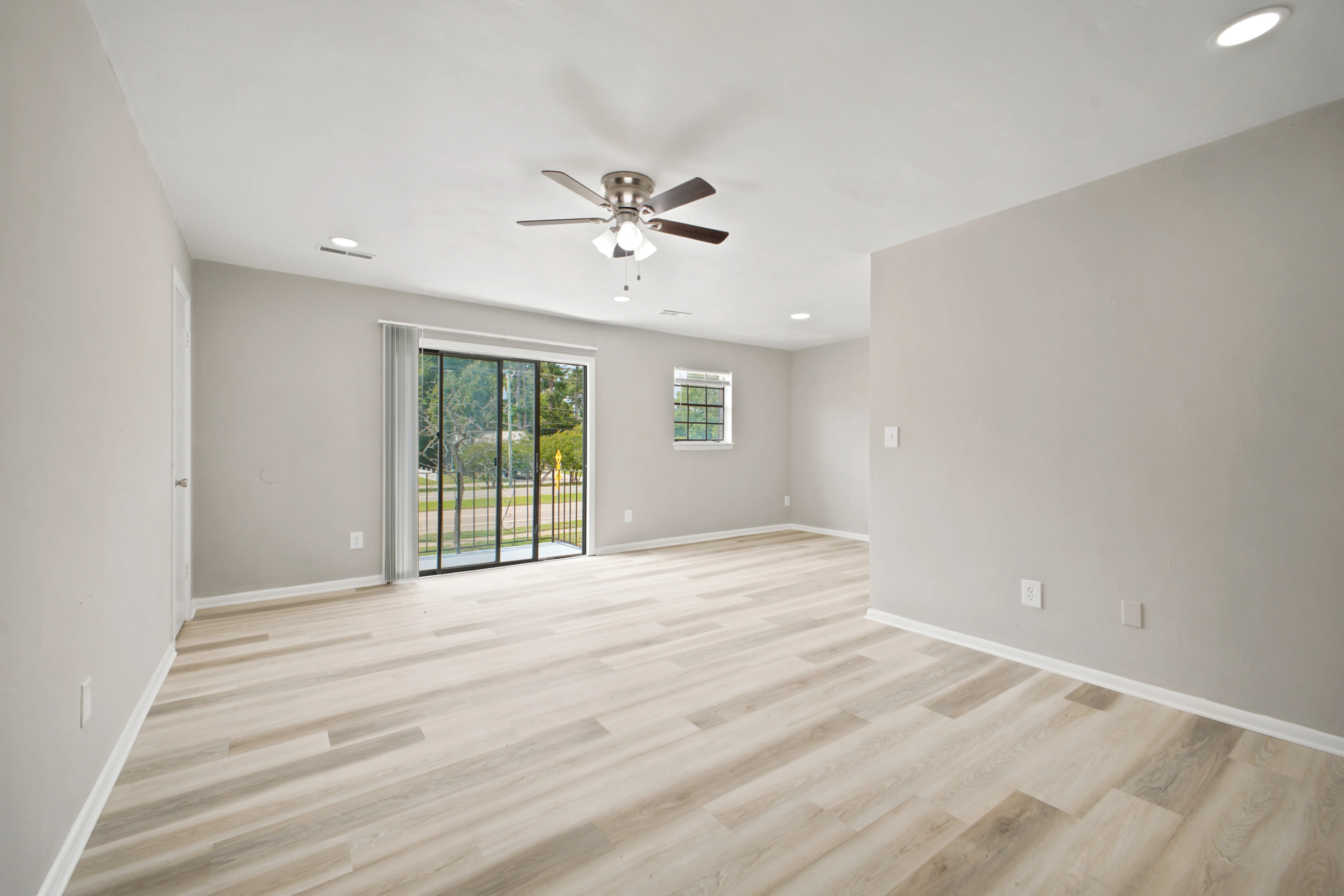 Spacious living room with ceiling fan and wood-look flooring