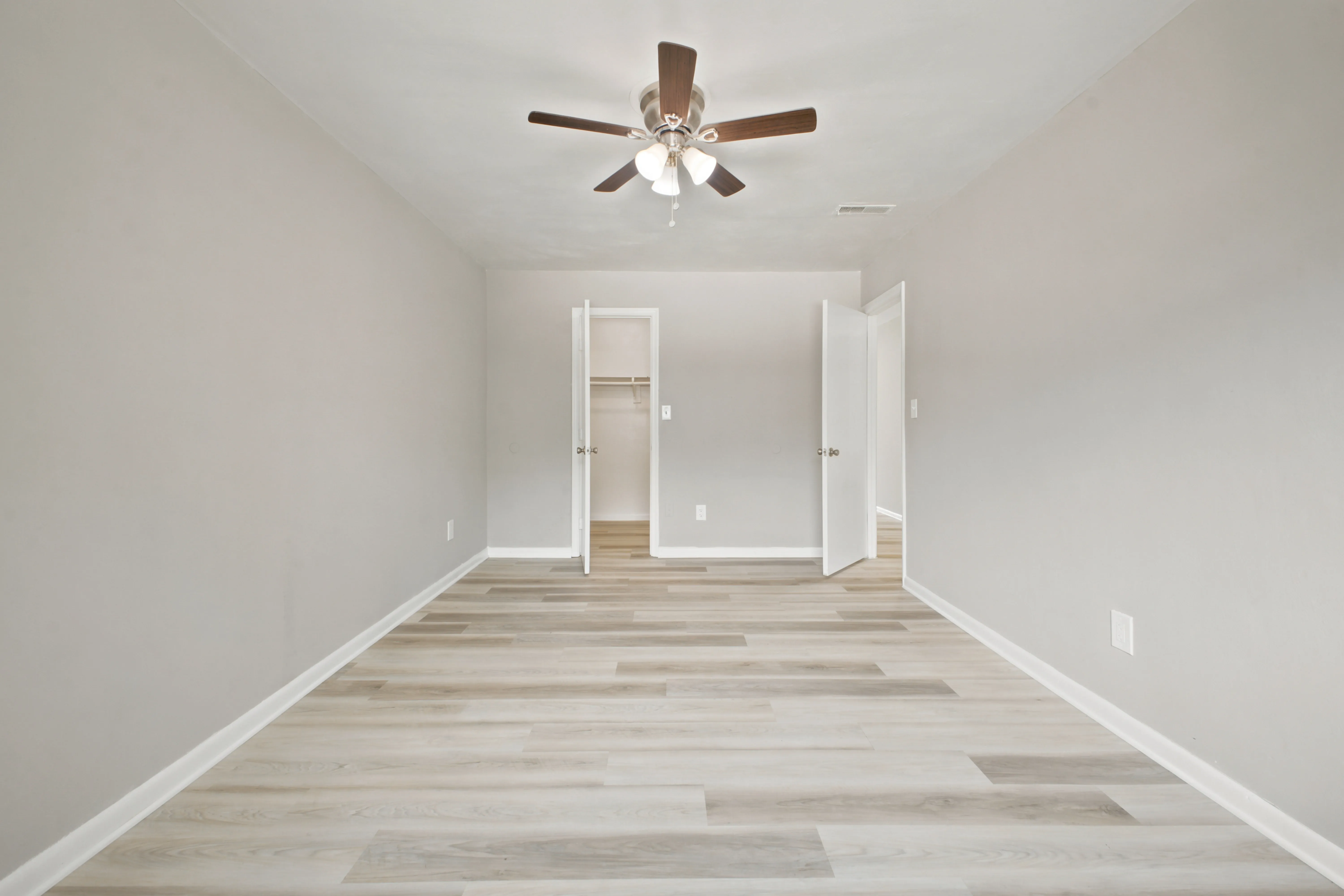 Primary bedroom with ceiling fan and walk-in closet